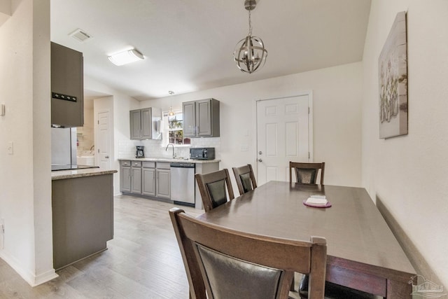 dining space featuring a chandelier, light wood-style flooring, visible vents, and baseboards