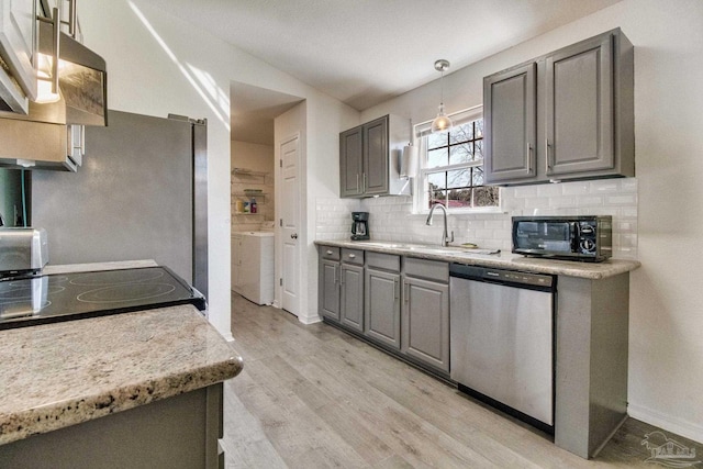 kitchen with independent washer and dryer, gray cabinets, dishwasher, and backsplash