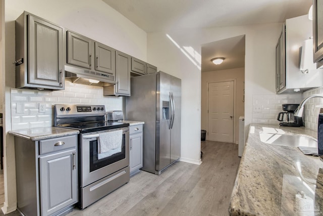 kitchen featuring stainless steel appliances, a sink, under cabinet range hood, and gray cabinetry