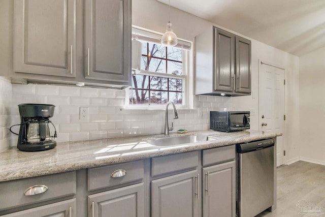 kitchen featuring black microwave, gray cabinetry, a sink, light wood-style floors, and stainless steel dishwasher