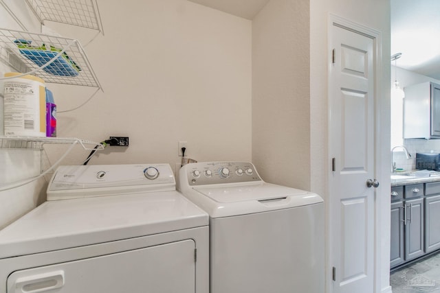 clothes washing area featuring laundry area, independent washer and dryer, and a sink