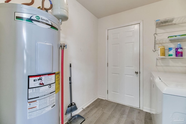 laundry room featuring electric water heater, laundry area, separate washer and dryer, baseboards, and light wood-style floors