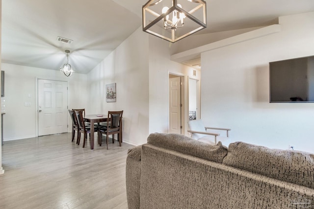 living area with lofted ceiling, visible vents, baseboards, light wood-style floors, and an inviting chandelier