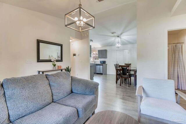 living area with a chandelier, light wood-type flooring, and visible vents