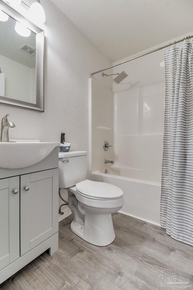 full bathroom with toilet, visible vents, wood finished floors, and vanity