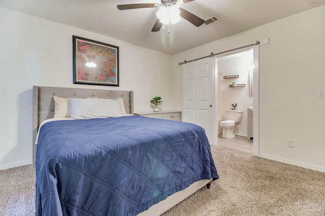 bedroom with ensuite bathroom, carpet floors, a barn door, and visible vents