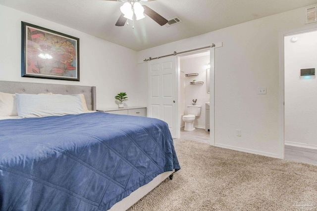 carpeted bedroom featuring baseboards, visible vents, ensuite bathroom, and a barn door