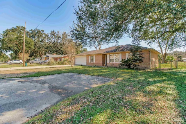 ranch-style house featuring an attached garage, brick siding, fence, and a front yard