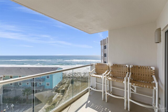 balcony featuring a view of the beach and a water view