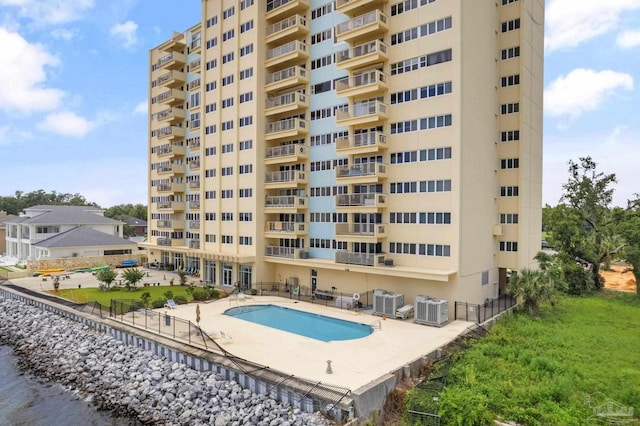 view of pool featuring central AC unit, a water view, and a patio