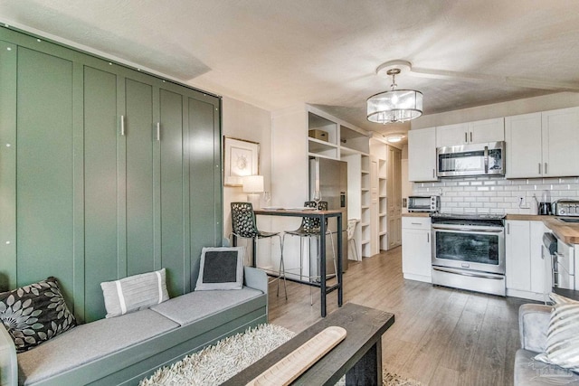 224 E Garden St Unit 236, Pensacola, FL 32502 - kitchen featuring pendant lighting, wood-type flooring, white cabinets, backsplash, and stainless steel appliances