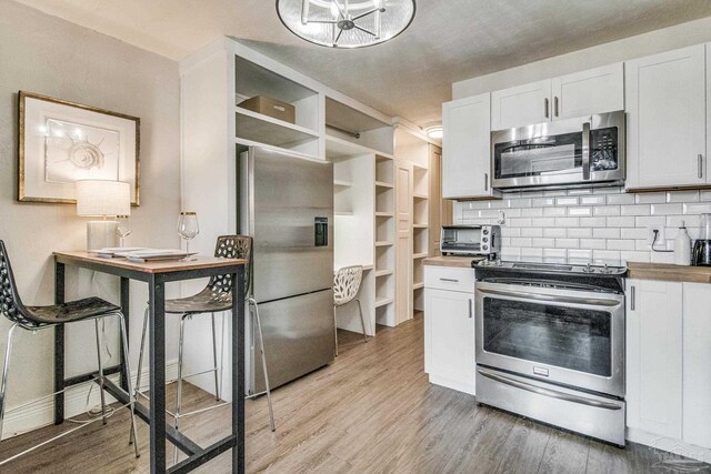 224 E Garden St Unit 236, Pensacola, FL 32502 - kitchen featuring wooden counters, appliances with stainless steel finishes, white cabinetry, tasteful backsplash, and light wood-type flooring
