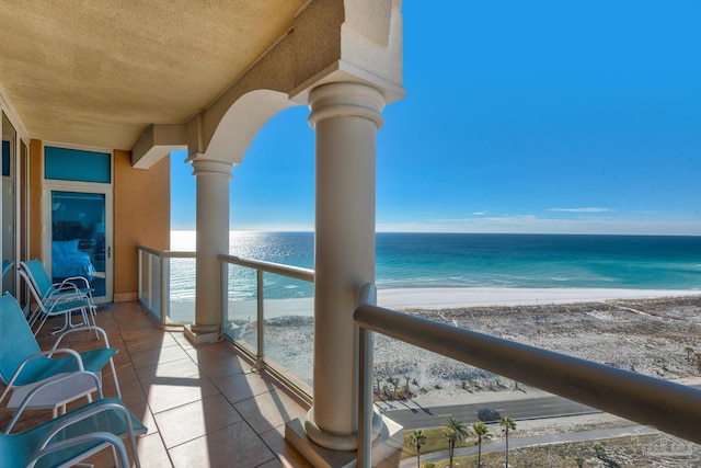 balcony featuring a view of the beach and a water view