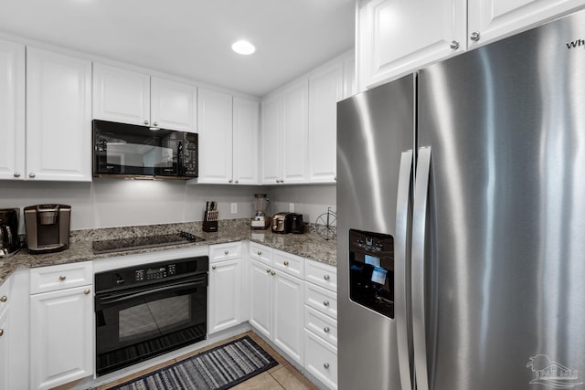 kitchen with white cabinetry, dark stone counters, and black appliances