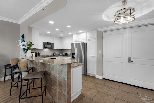 kitchen featuring kitchen peninsula, stainless steel fridge, decorative light fixtures, light stone counters, and white cabinetry