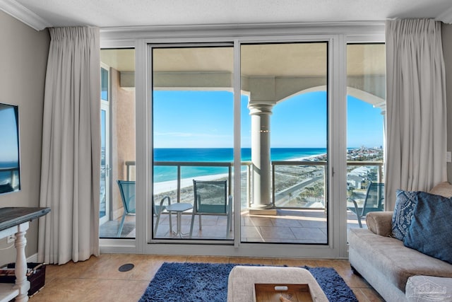 tiled living room featuring a textured ceiling, a water view, a view of the beach, and ornamental molding