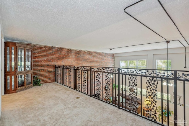 hall featuring brick wall, carpet flooring, and a textured ceiling