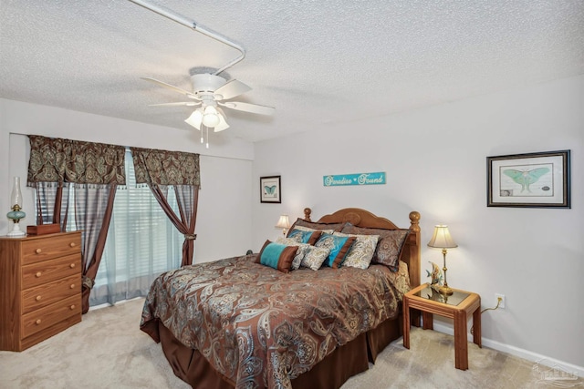 bedroom featuring ceiling fan, light colored carpet, and a textured ceiling