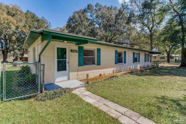 view of front facade featuring concrete block siding, a front lawn, and fence