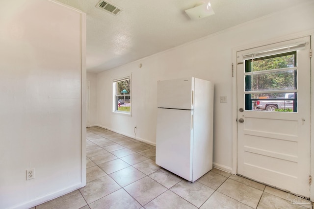 kitchen with light tile patterned floors, baseboards, visible vents, and freestanding refrigerator