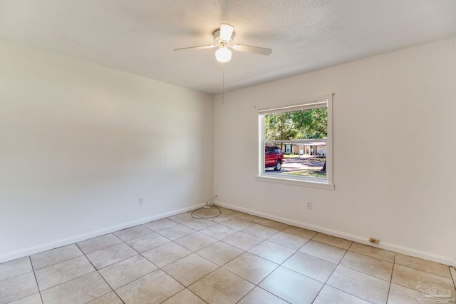 empty room with light tile patterned flooring, a ceiling fan, baseboards, and a textured ceiling