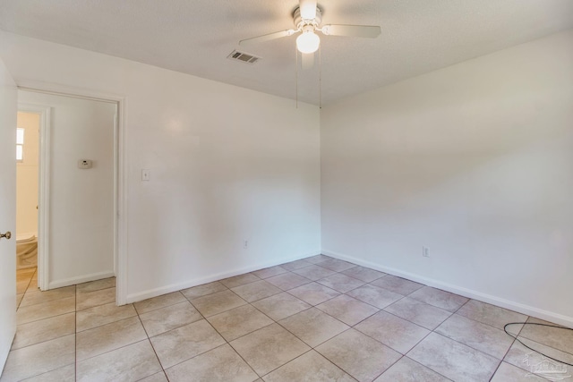 spare room featuring light tile patterned floors, visible vents, baseboards, and a ceiling fan