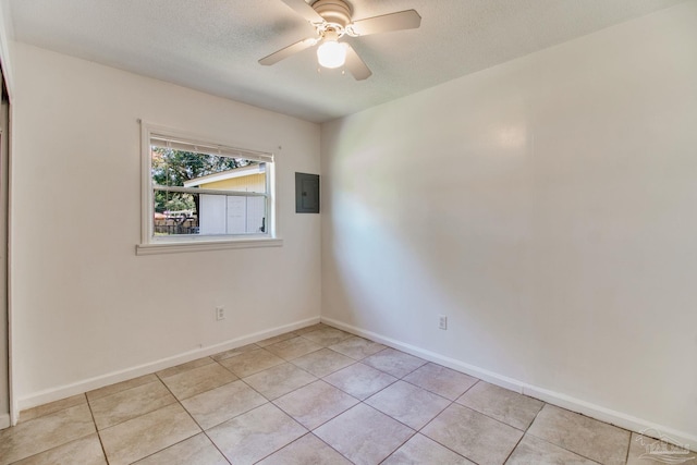 spare room with a ceiling fan, electric panel, a textured ceiling, light tile patterned floors, and baseboards