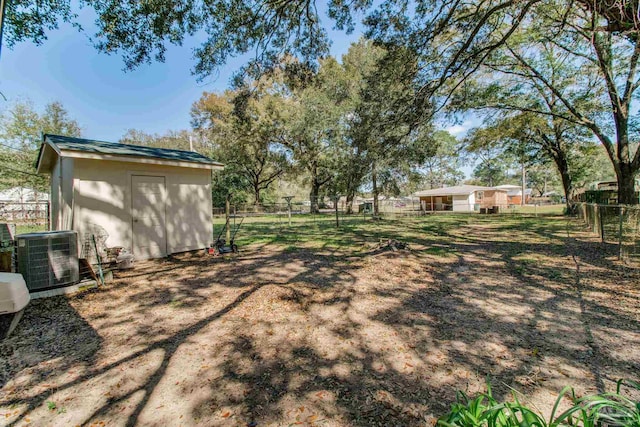 view of yard with cooling unit, fence, an outdoor structure, and a shed