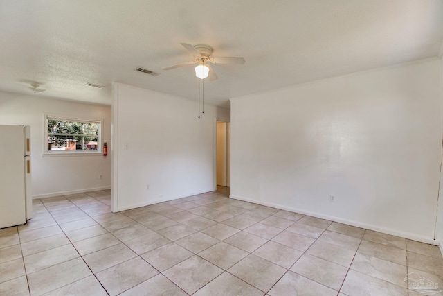 empty room featuring light tile patterned floors, visible vents, a textured ceiling, and a ceiling fan