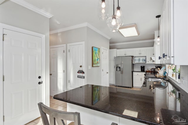 kitchen featuring kitchen peninsula, light tile patterned floors, appliances with stainless steel finishes, decorative light fixtures, and white cabinetry