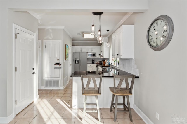 kitchen with white cabinetry, kitchen peninsula, a kitchen bar, light tile patterned floors, and appliances with stainless steel finishes