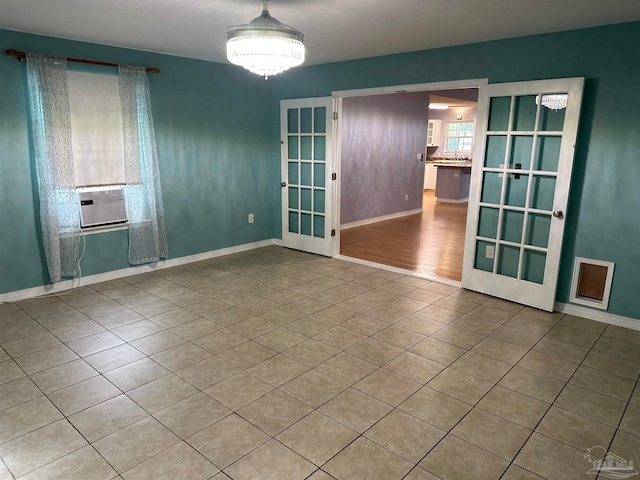 empty room with french doors, a notable chandelier, and light wood-type flooring