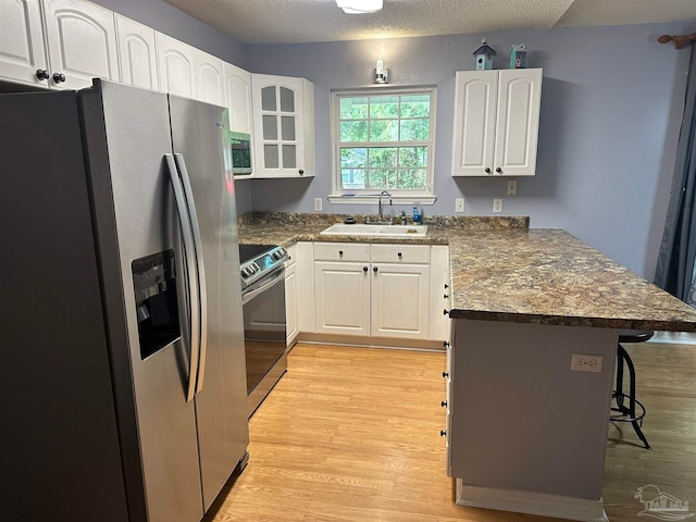 kitchen featuring appliances with stainless steel finishes, a breakfast bar area, white cabinetry, and sink