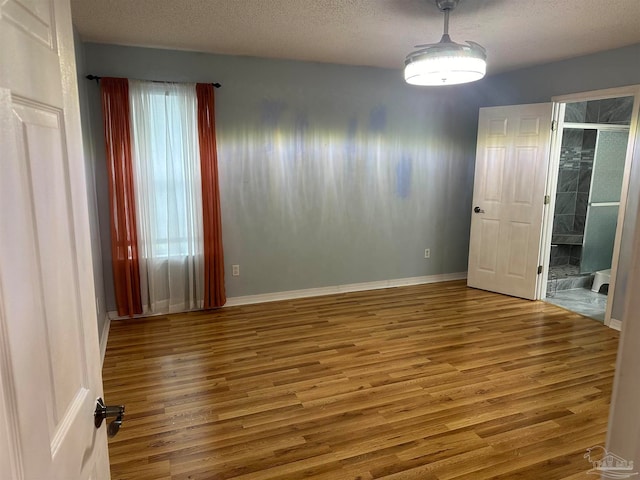 unfurnished room with a textured ceiling and hardwood / wood-style floors