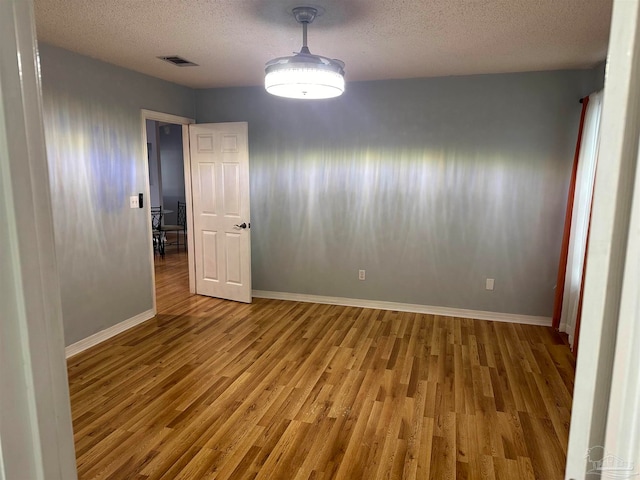 unfurnished room featuring hardwood / wood-style flooring and a textured ceiling