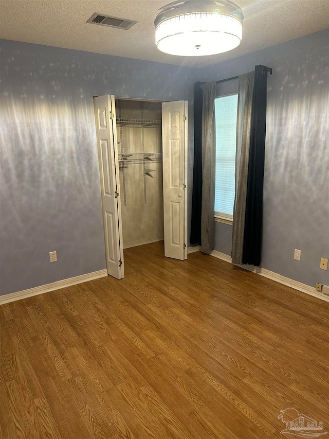 unfurnished bedroom with hardwood / wood-style flooring, a closet, and a textured ceiling