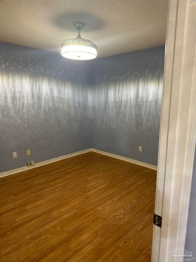 unfurnished room with a textured ceiling and dark hardwood / wood-style floors