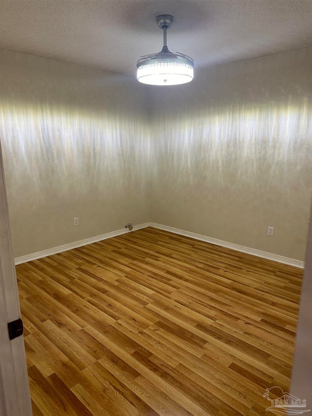 unfurnished room with a textured ceiling and wood-type flooring
