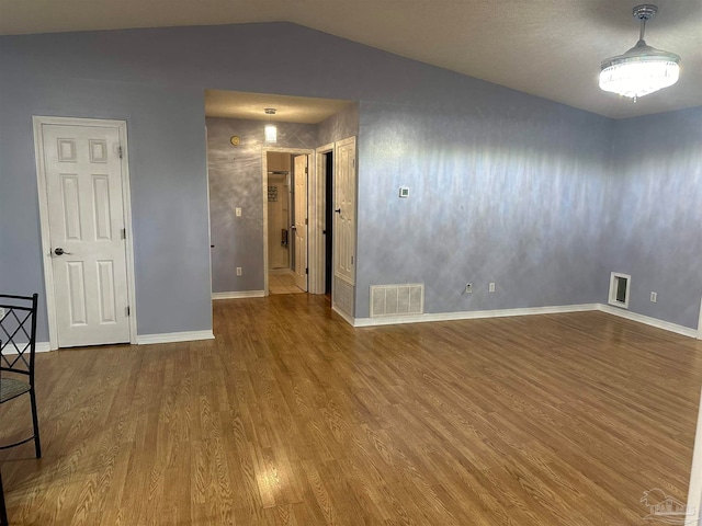 spare room with wood-type flooring and vaulted ceiling