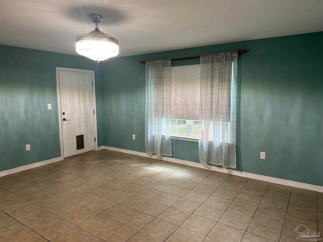 spare room with an inviting chandelier and tile patterned floors