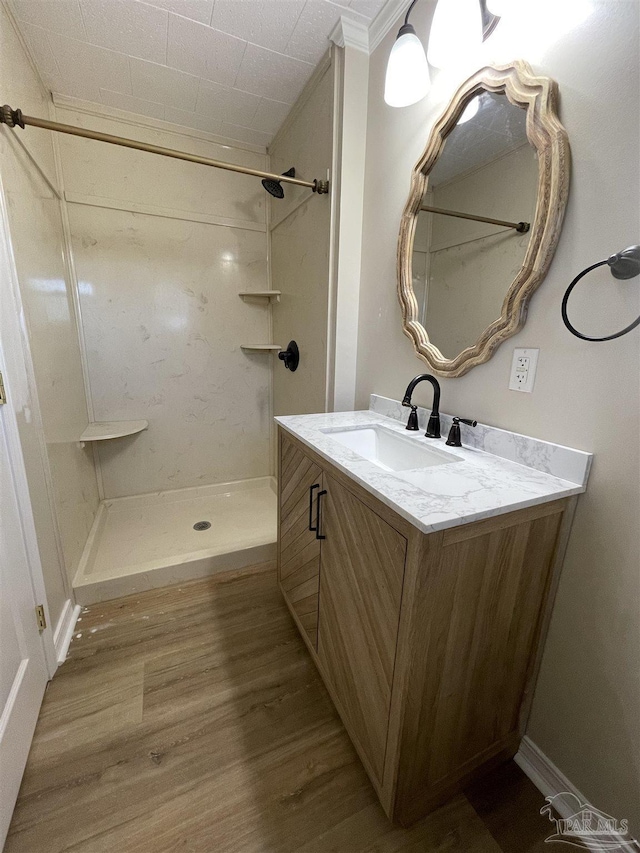 bathroom with vanity, hardwood / wood-style floors, ornamental molding, and a shower