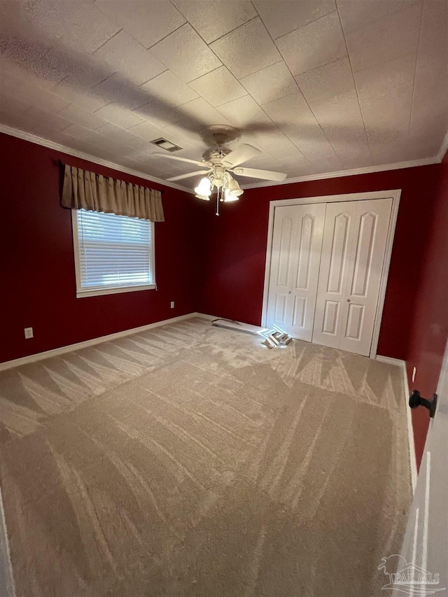 unfurnished bedroom with crown molding, carpet, ceiling fan, and a closet