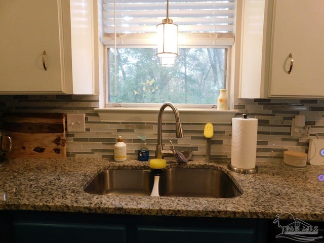 kitchen with backsplash, stone countertops, white cabinetry, and sink