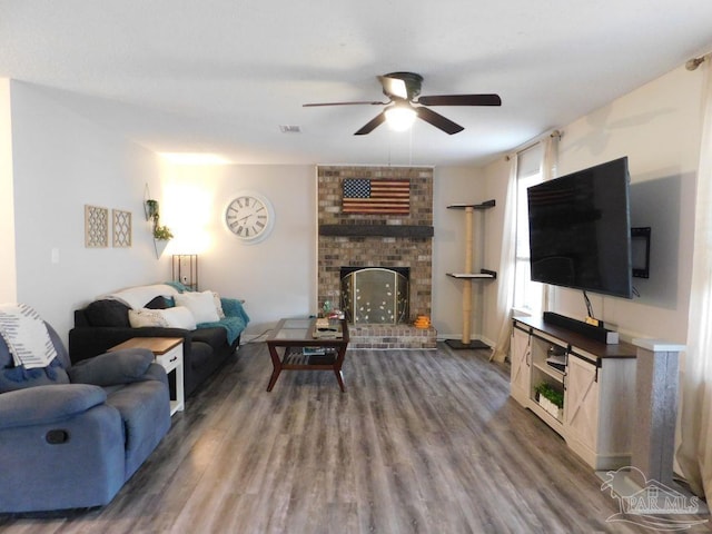 living room with hardwood / wood-style flooring, ceiling fan, and a brick fireplace