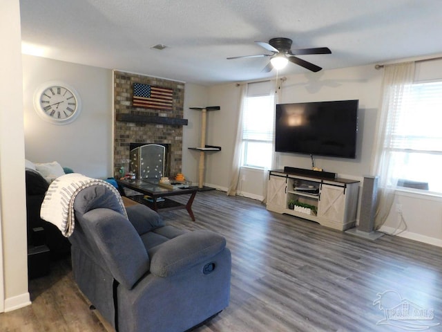 living room featuring ceiling fan, hardwood / wood-style floors, and a brick fireplace