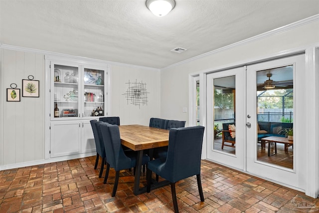 dining room with a textured ceiling, french doors, and crown molding