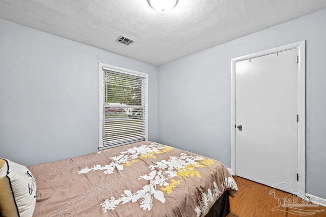 bedroom with a textured ceiling and hardwood / wood-style flooring