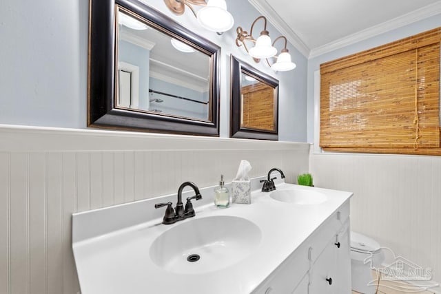 bathroom with toilet, vanity, wooden walls, and crown molding