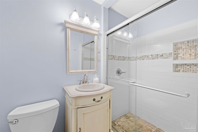 bathroom with vanity, toilet, and a shower with door