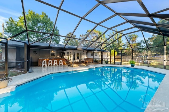 view of swimming pool with glass enclosure and a patio area